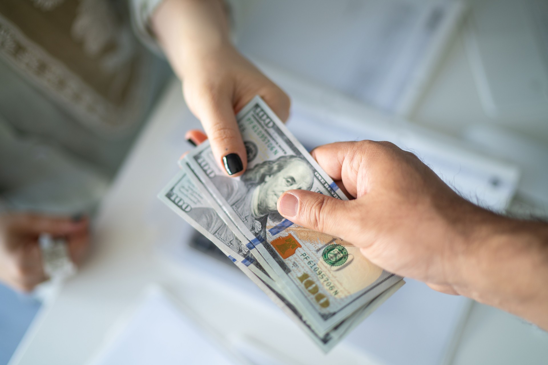 Close-up of counting and giving American dollar banknotes in hand, business and finance concept