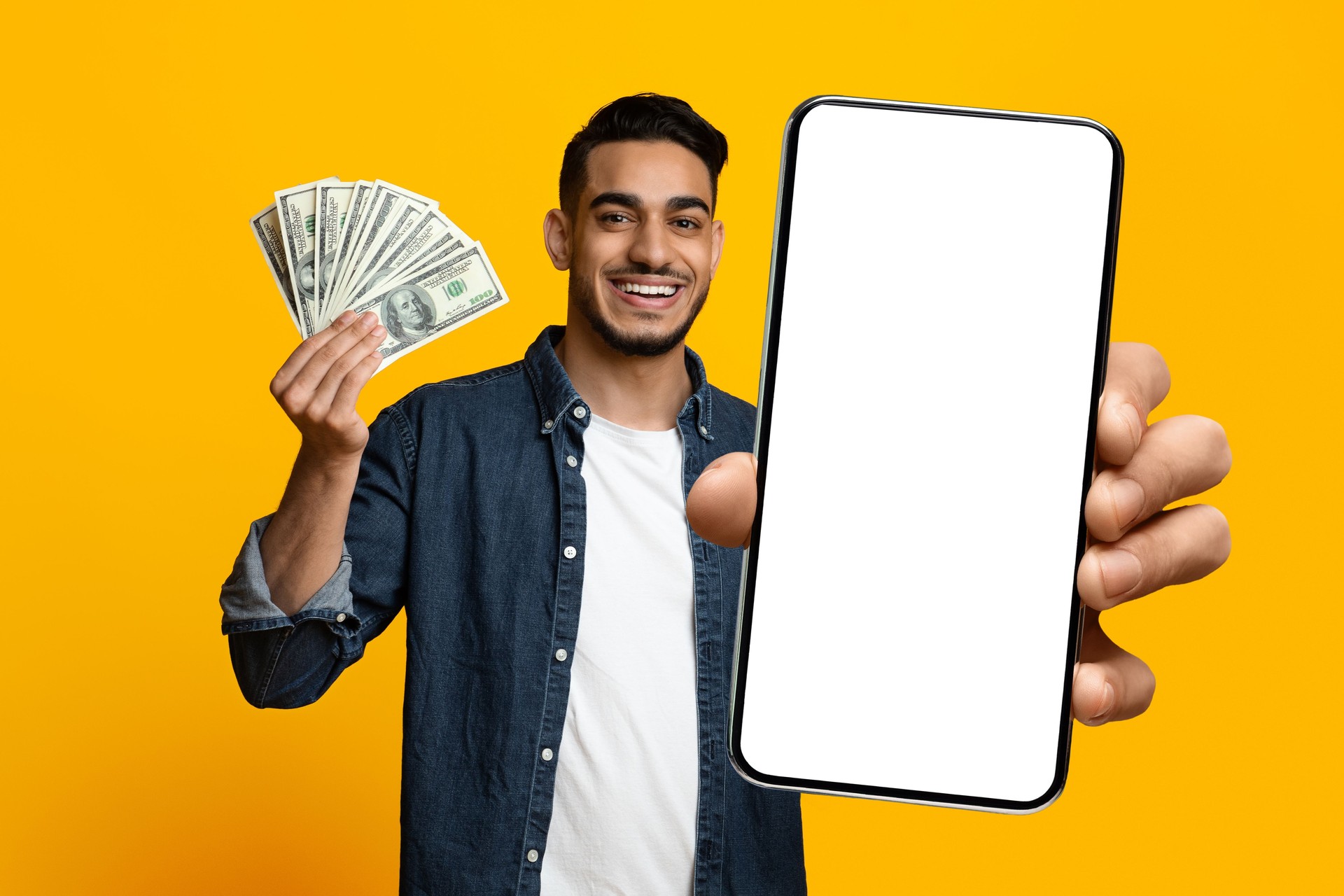 Positive handsome middle eastern guy showing cell phone and cash
